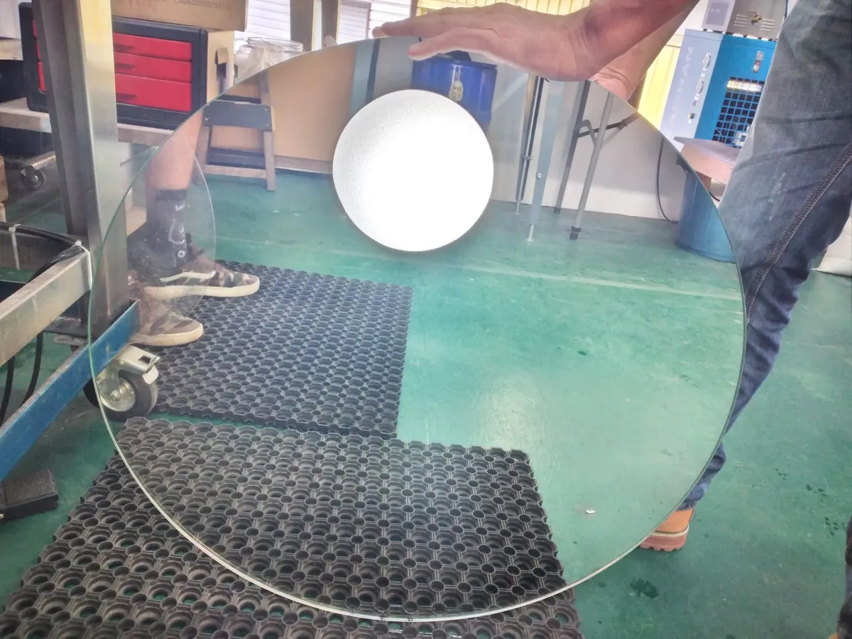 Technicien tenant une vitre ronde après fumage/traitement PRO-GLASS en atelier